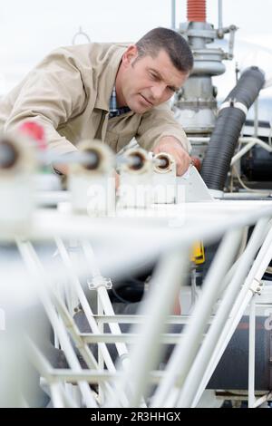 man measuring off metal bar in workshop Stock Photo