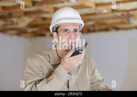 construction foreman talking on walkie-talkie holding clipboard Stock Photo