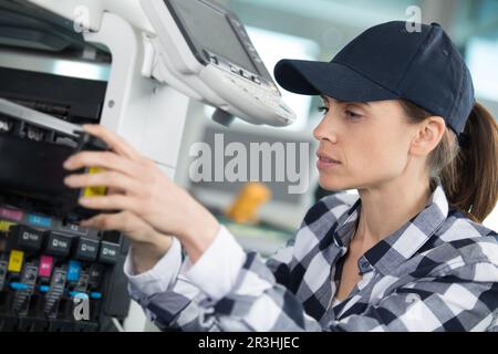 woman checking the ink levels on a professional printer Stock Photo