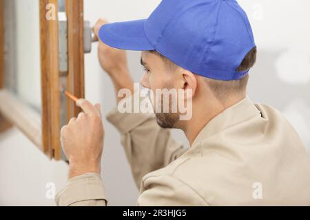 smiling man is fixing a window handle Stock Photo