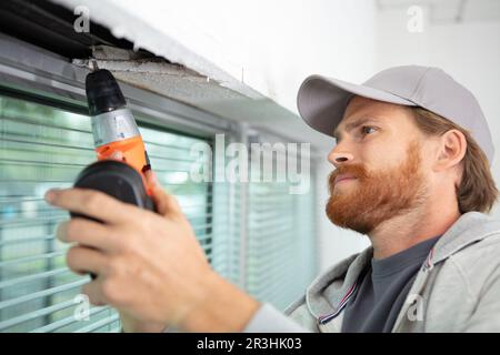man installing roller shutter on window Stock Photo