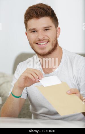 young man pulling letter from envelope Stock Photo