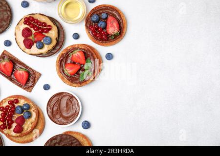 Fresh rye crispbreads, crunchy rice cakes and rusks with different toppings on light grey table, flat lay. Space for text Stock Photo