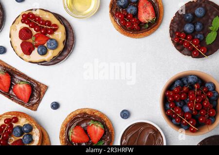 Fresh rye crispbreads, crunchy rice cakes and rusks with different toppings on light grey table, flat lay. Space for text Stock Photo
