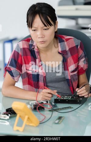 female asian computer technician using multimeter Stock Photo