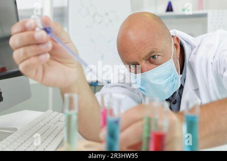 man scientist using auto-pipette with flask in medical laboratory Stock Photo