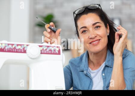 woman repairing sewing machine with screwdriver Stock Photo