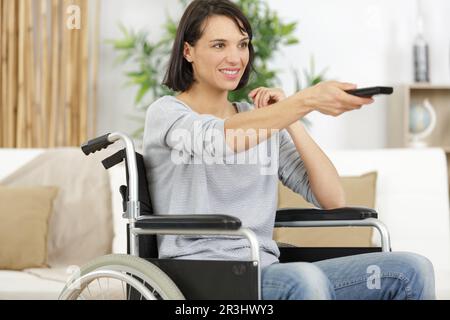 woman in wheelchair uses a tv remote control Stock Photo