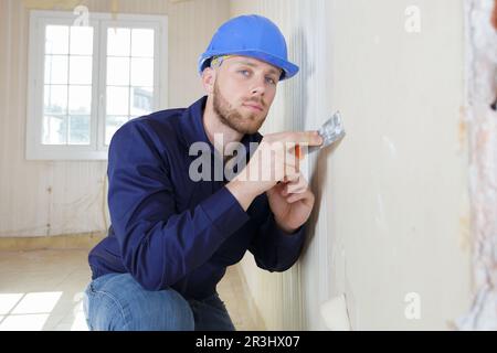 plasterer using scraper on wall Stock Photo