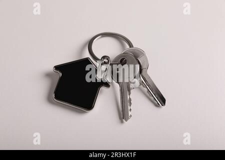 Keys with trinket in shape of house on white background, above view. Real estate agent services Stock Photo