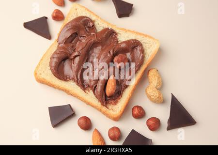 Tasty toast with chocolate paste and nuts on beige background, flat lay Stock Photo