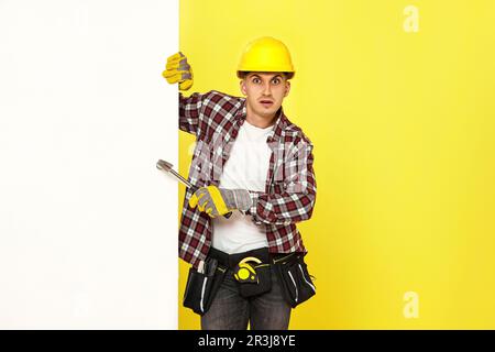 professional builder in work clothes in helmet holding hammer. copy space for text Stock Photo