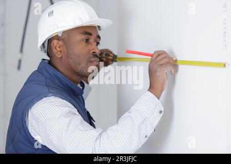 man measuring a wall using a folding ruler Stock Photo