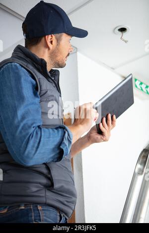 electrician repairing ceiling light at site Stock Photo
