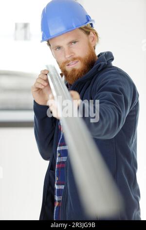 smiling construction worker carrying a metal bar Stock Photo