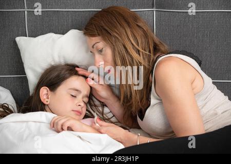 Mother taking care of her sick daughter. Stock Photo