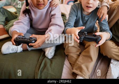 Closeup of children playing videogames together and holding controllers Stock Photo