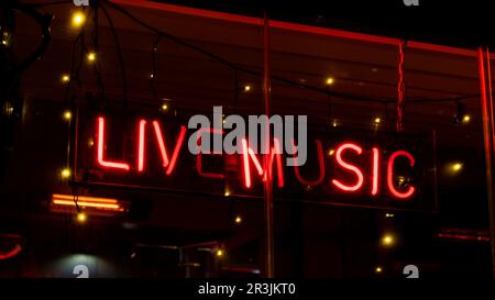 Live music inscription in neon lights at night. Electric sign at night nightlife concept. Modern fluorescent life style luminesc Stock Photo