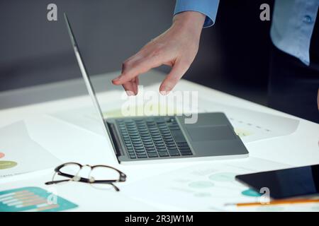Project manager discussing a new strategy of company with the team, pointing on laptop screen over modern office interior design. Concept of teamwork Stock Photo