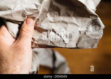 Paris, France - May 22, 2023: A male hand holds a Blauer-Engel paper package, showcasing an eco-friendly lifestyle indoors. The packaging is made from 100 recycled materials and has manufactured by Papier Sprick. Stock Photo