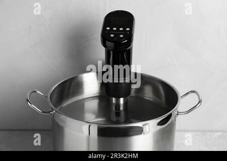 Sous vide cooker in pot on light grey table. Thermal immersion circulator Stock Photo