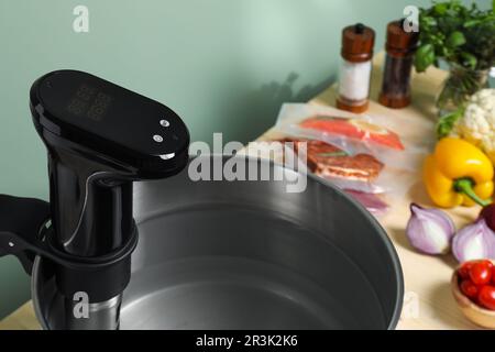 Sous vide cooker in pot and ingredients on table, closeup. Thermal immersion circulator Stock Photo