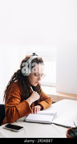 Young woman elearning from home, attending virtual class and remote conference meetings on laptop. Female student distance learning at home with Stock Photo