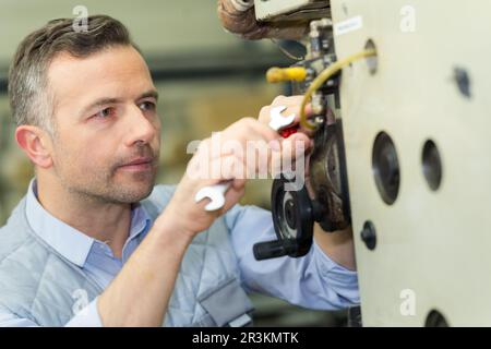 male technician using spanner machinery Stock Photo