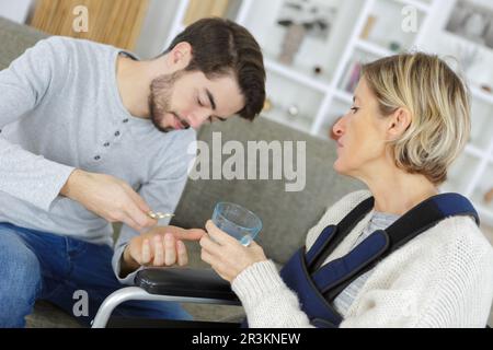 close-up of son giving ill person medicines Stock Photo