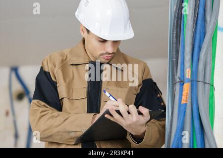 young male contractor making notes on clipboard Stock Photo