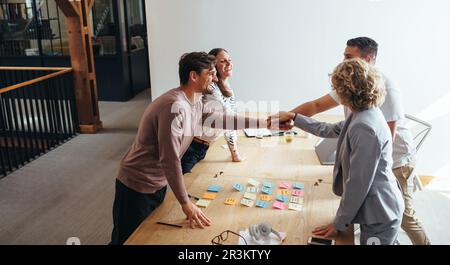 Professionals stacking hands together during a meeting in an office. Creative business people working together on a project. Teamwork and collaboratio Stock Photo