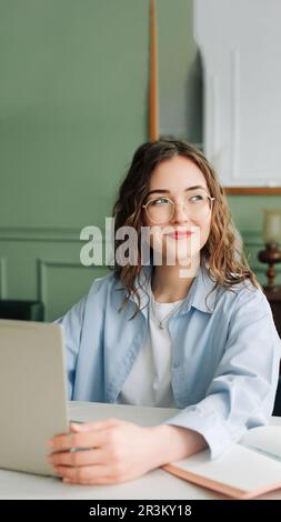 Smiling female corporate employee working on laptop in modern office, marketing manager or businesswoman focused on screen, happy and confident at her Stock Photo