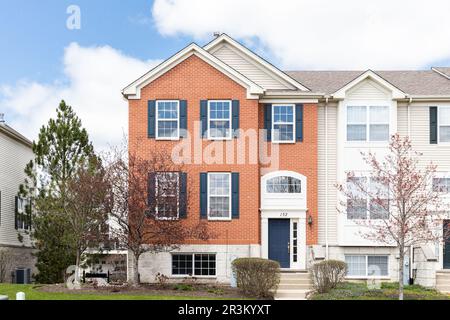 A new townhouse with a red brick siding and blue shutters and front door. Stock Photo