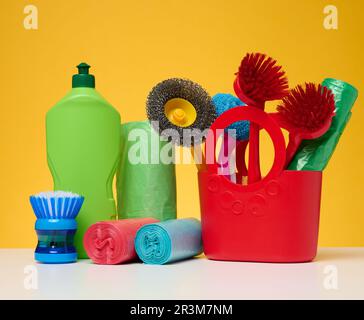 Plastic basket with brushes, disinfectant in a bottle on a yellow background. Stock Photo