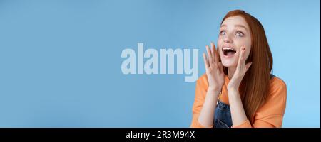 Attractive silly european redhead young girl 20s calling friend searching someone crowd look relaxed joyfully yelling hold hands Stock Photo