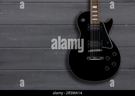Black electric guitar on a distressed grey wooden backgound with a drop shadow and space for copy Stock Photo