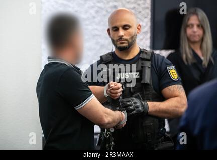 Stuttgart, Germany. 24th May, 2023. A man accused of the crime is led by a court official into a room at Stuttgart Regional Court - as he does so, his handcuffs are taken off at his seat. The 36-year-old defendant is accused of killing a 17-year-old girl in July 2022. Credit: Christoph Schmidt/dpa/Alamy Live News Stock Photo