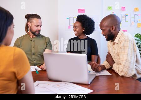 Diverse team of four mobile app developers discuss design during meeting Stock Photo