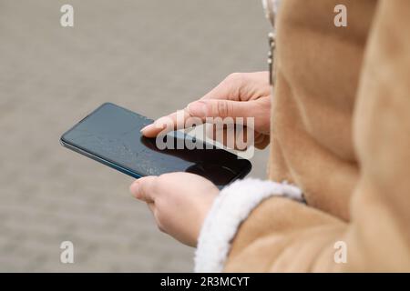 Woman holding damaged smartphone outdoors, closeup. Device repairing Stock Photo