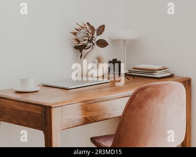Modern workplace in room decorated. Living room office with home decor. Beautiful workspace - wooden table with laptop - online remote work from home Stock Photo