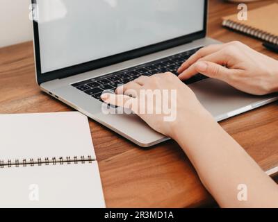 Woman working at home office hand on keyboard. Home workspace - wooden table laptop. Beautiful workspace - online remote work from home concept. close Stock Photo