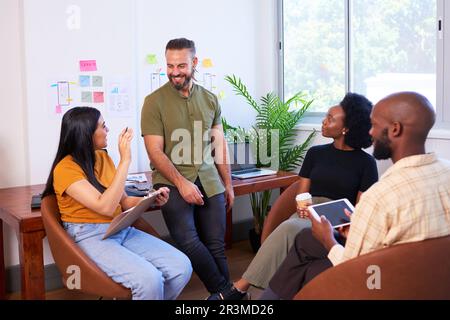 Four diverse team members having informal meeting, sitting in creative office Stock Photo