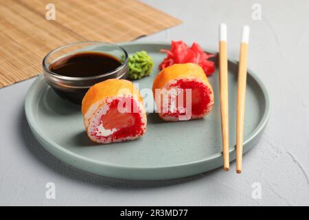 Delicious sushi rolls, soy sauce, wasabi, ginger and chopsticks on grey textured table, closeup Stock Photo