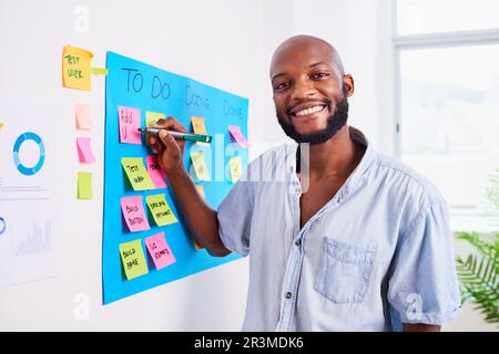 Black developer writes ticket on scrum board, sprint planning coding meeting Stock Photo