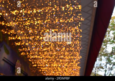 Blurred view of beautiful lights hanging from ceiling outdoors. Bokeh effect Stock Photo