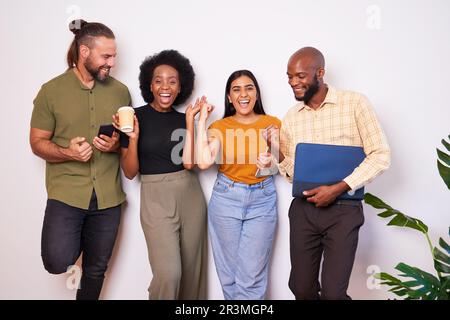 Diverse creative tech team lean against wall and celebrates success, cheer smile Stock Photo