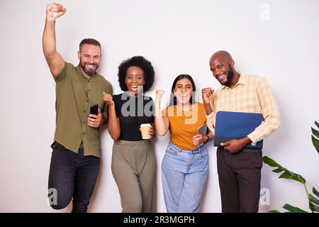 Diverse creative tech team lean against wall and celebrates success, cheer smile Stock Photo