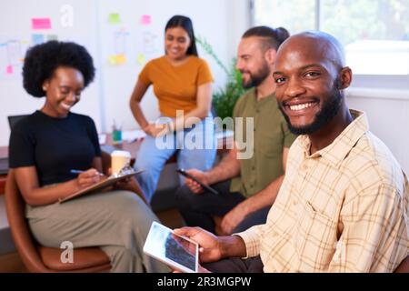 Smiling Black developer man with team having informal meeting, creative office Stock Photo