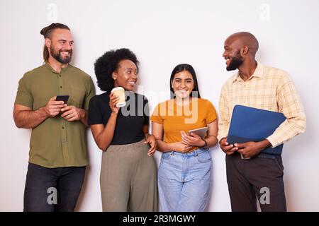 Diverse creative tech team lean against wall and take a break, talking smiling Stock Photo