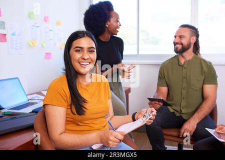 Smiling Indian woman with team having informal meeting, creative office Stock Photo